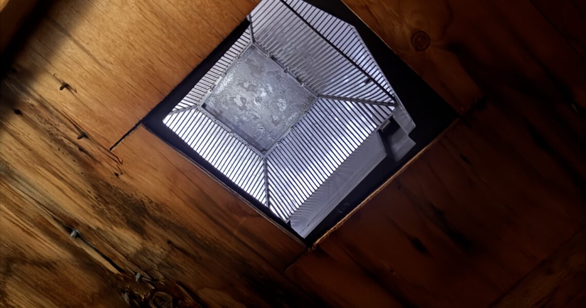 A view looking up at a small, square skylight window set in a wooden ceiling, allowing natural light to enter the space—ideal for inspecting woodwork or considering attic mold removal Aurora professionals recommend.
