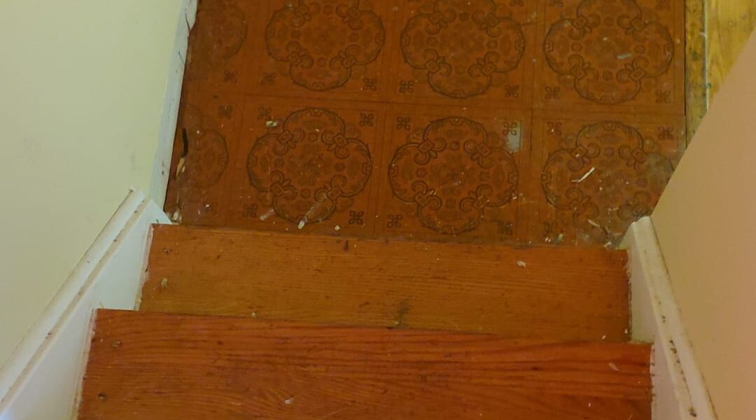 old patterned vinyl floor tiles discovered at basement stair landing in Toronto home