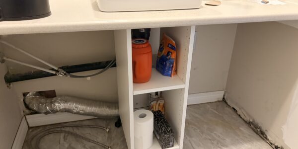 Visible mold growth along the lower drywall and baseboards inside an Oakville laundry room prior to professional mold remediation.