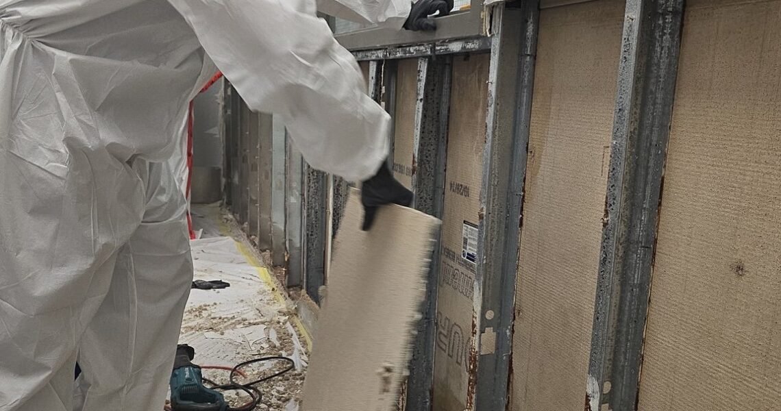 Technician removing affected drywall under controlled conditions